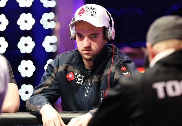 Poker pro and WSOP MI Ambassador Joe Cada sits at a poker table with a serious look of determination on his face. He wears a white pokerstars baseball cap and navy pokerstars jacket.