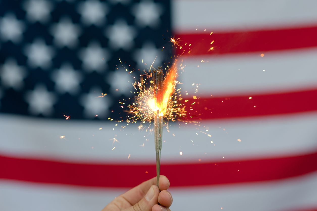 an american flag is seen in the background. in front of it, a hand holds a sparkler. Four states are better than three, right? Michigan joining Nevada, New Jersey, and Delaware in their online poker compact is BIG news. Here's why.