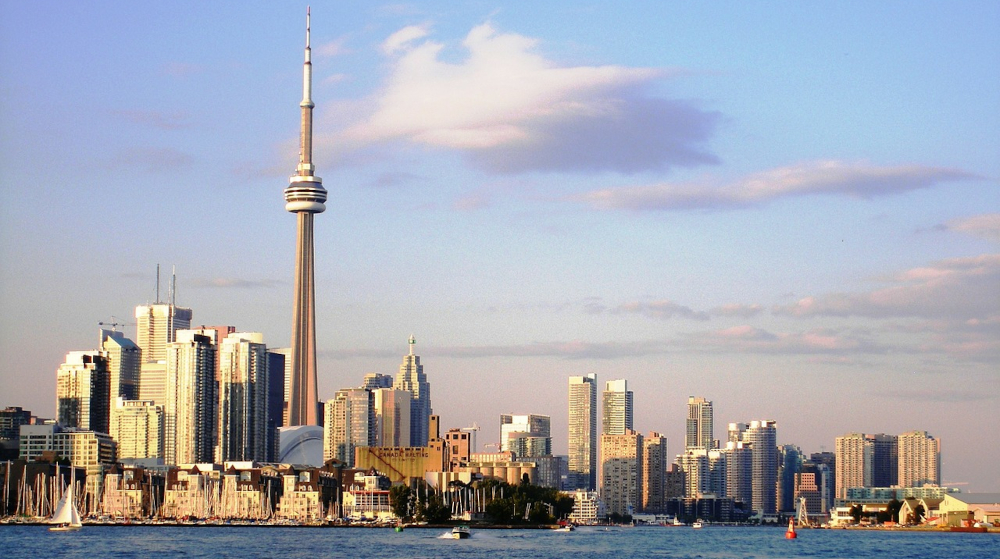 Toronto skyline is seen against blue sky. CN Tower and skyscrapers rise up from the shore of Lake Ontario. Ontario, Canada's biggest province, is set to launch its new regulated iGaming market on April 4.